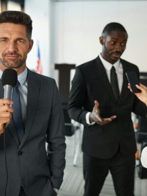 A journalist interviews a businessman in a conference room, capturing a professional and political setting.