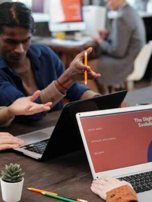 Diverse team collaborating with laptops in a modern office setting, discussing digital evolution.