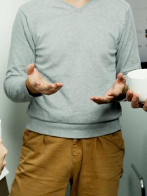 Team members engaged in a casual discussion with coffee cups in hand during an office meeting.